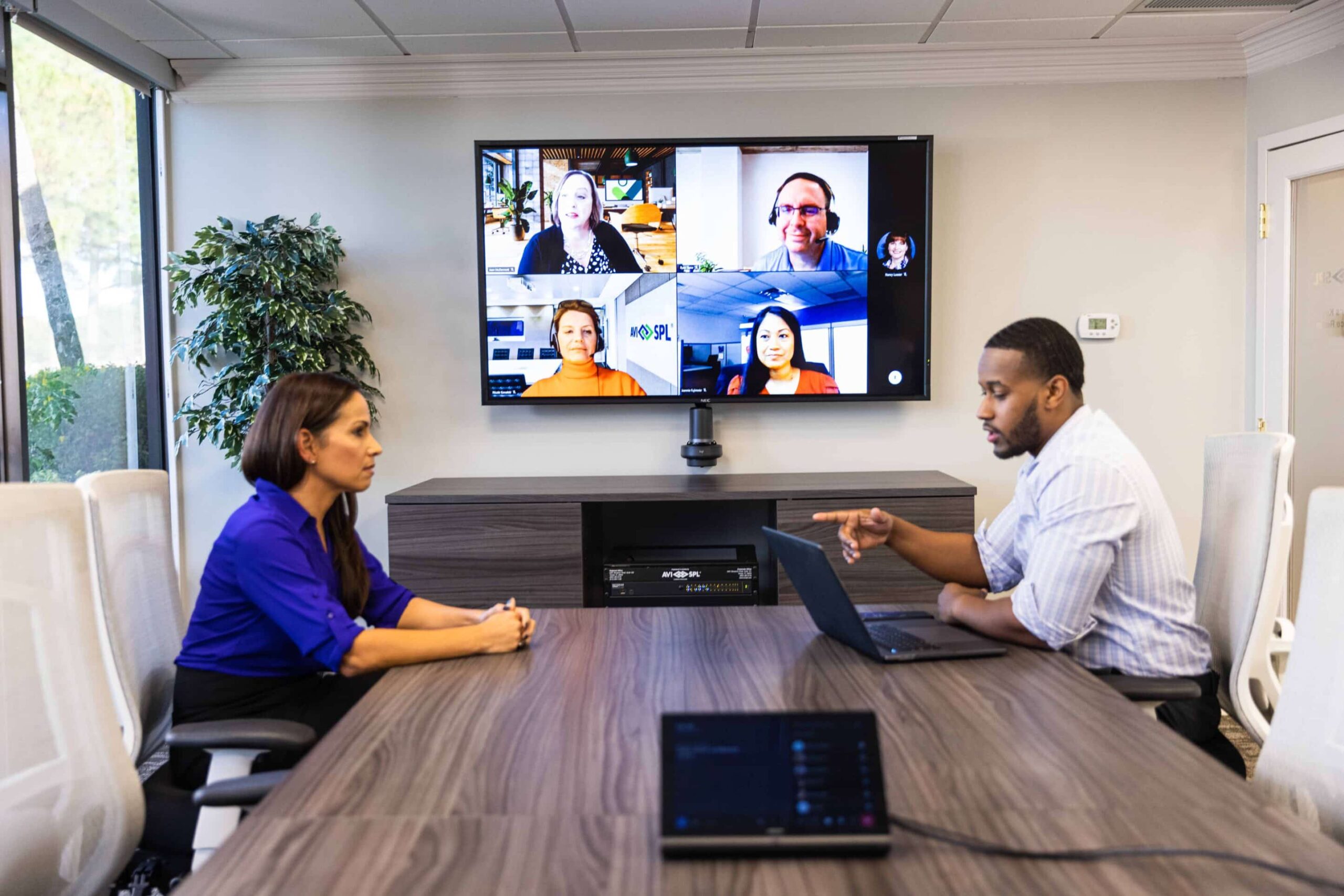 Virtual conference in a meeting room with remote participants on a large monitor